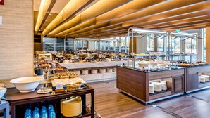 Un área de buffet con varias estaciones de servicio, una encimera de mármol y un techo de madera.