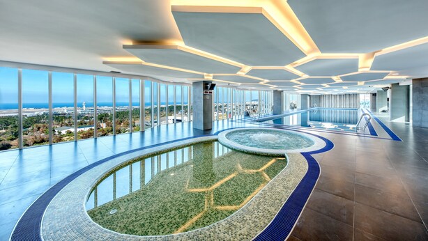 Un área de piscina interior moderna con vistas a la ciudad y al océano.