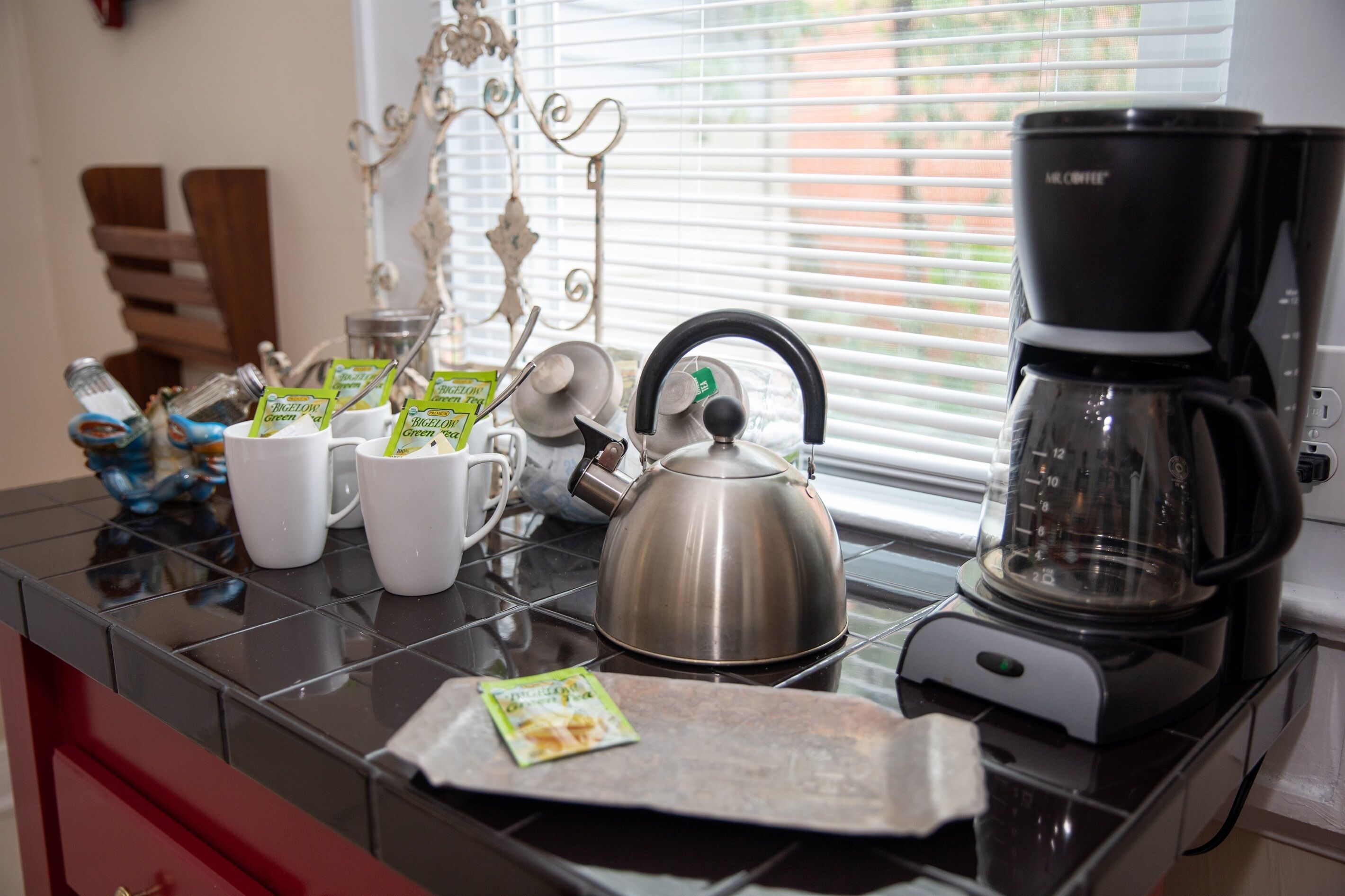 Eine Küchenarbeitsplatte mit Kaffeemaschine, Wasserkocher und Tassen.