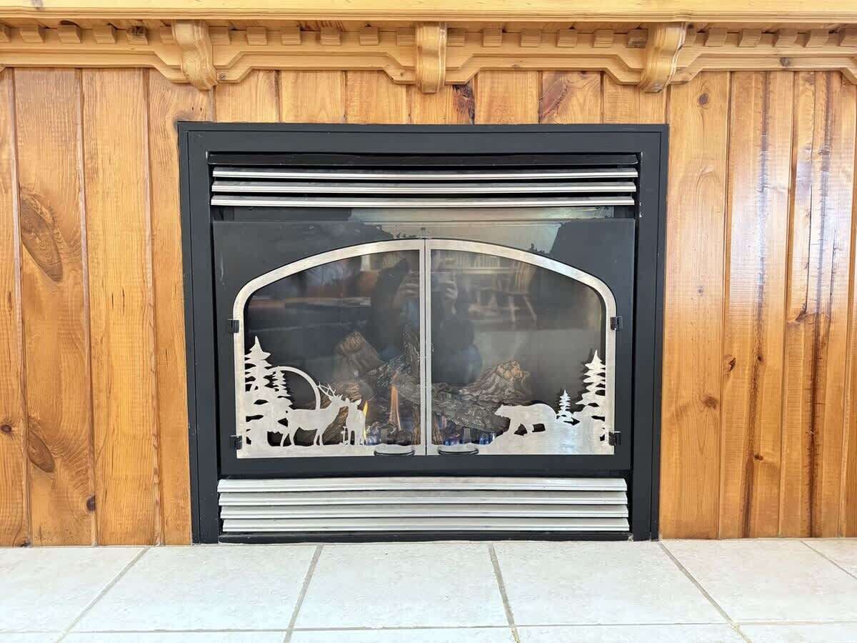 A wooden paneled wall with a black-framed window featuring a decorative cut-out of a winter scene.
