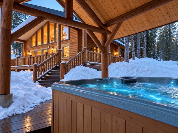 A wooden lodge with a hot tub and a staircase leading to a deck.