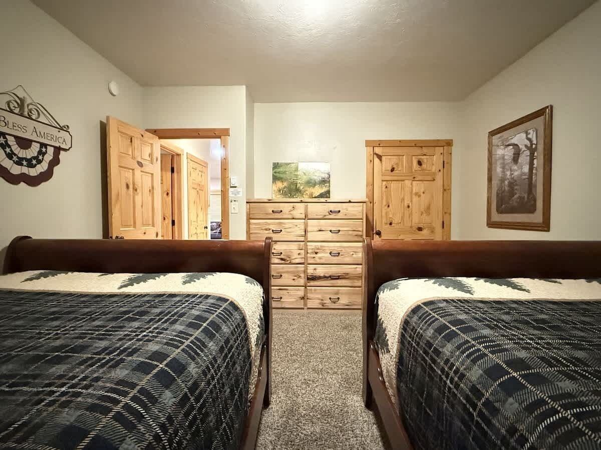 Un dormitorio con dos camas, un aparador y una puerta que da a otra habitación.