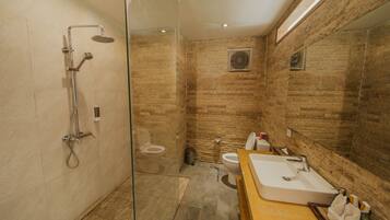 Un baño moderno con ducha envuelta en vidrio, tocador de madera con lavamanos y un inodoro.