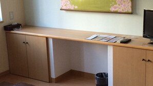 Una habitación con un escritorio de madera, una computadora y un cubo de basura.