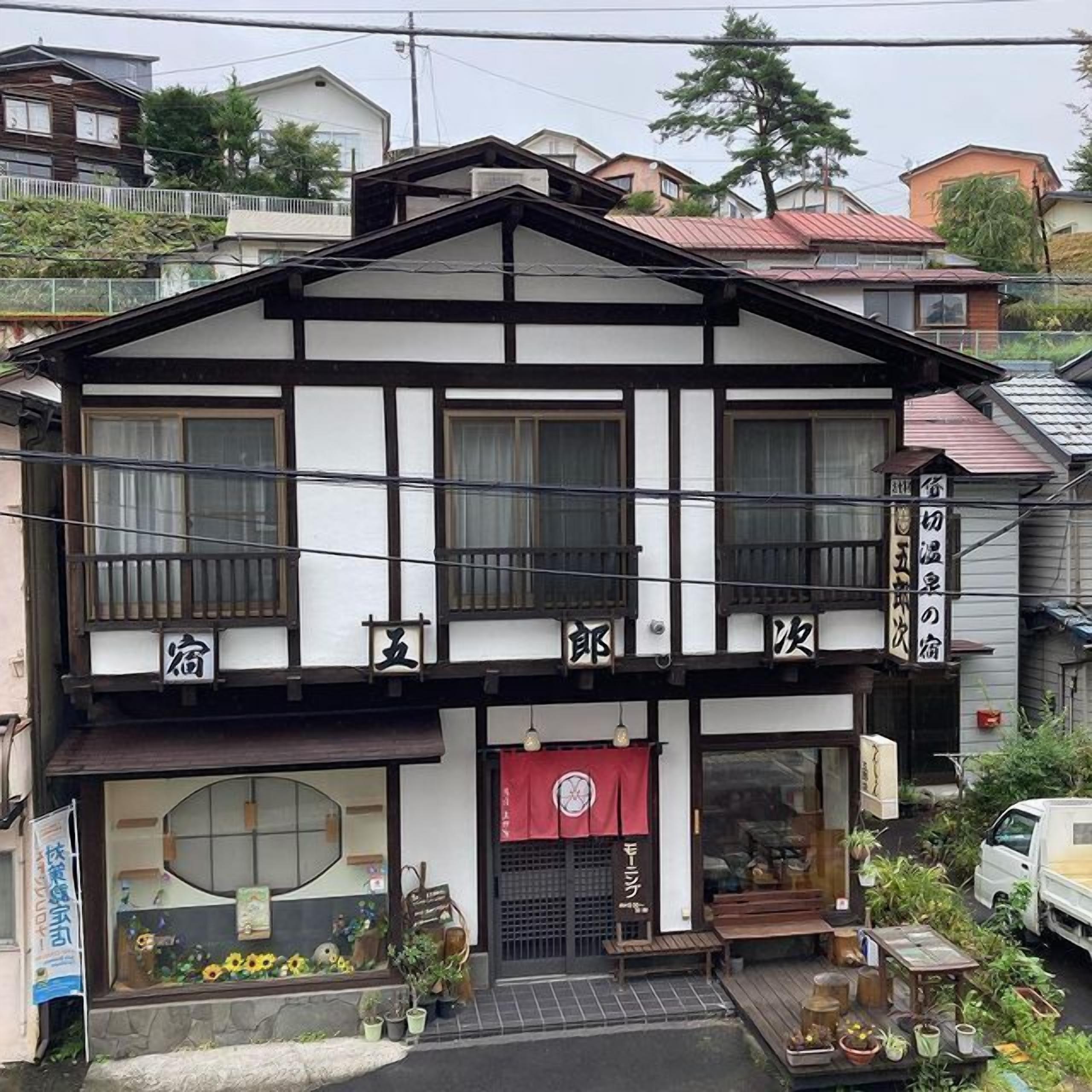 A traditional Japanese building with a two-story structure, a balcony, and a storefront with a red awning.