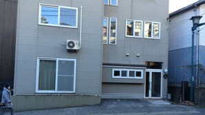 Un edificio de varios pisos con fachada plana, ventanas grandes y una puerta con panel de vidrio.