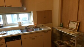 Una cocina con ventana, lavamanos y una vitrina de vidrio con revistas.