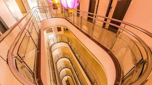 A multi-level interior with glass railings and a central spiral staircase. - Plazza hotel , Trichy (Tiruchirappalli)
