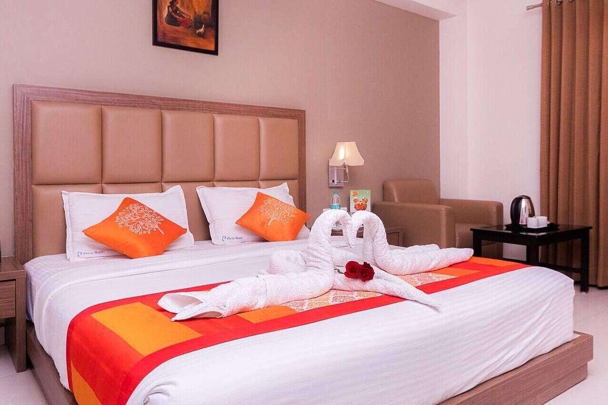 A hotel room with a large bed, two pillows, a nightstand, a chair, a desk, and a lamp.