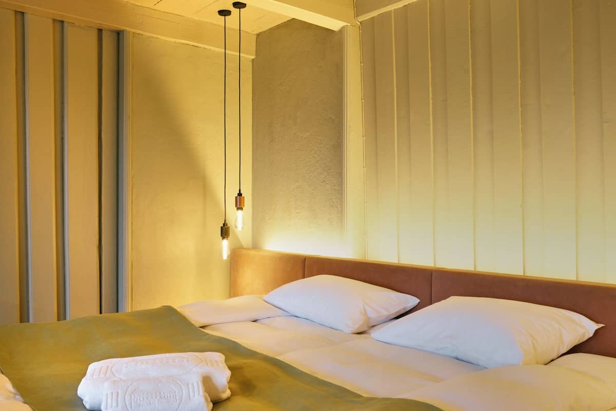 Ein Hotelzimmer mit einem Bett, Kissen, einer Decke und einem Handtuch auf dem Bett.