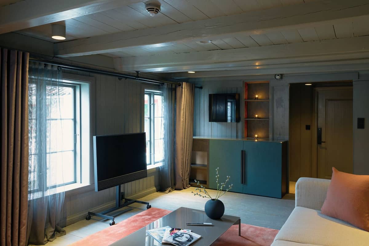 Ein modernes Wohnzimmer mit Flachbildfernseher, Couchtisch mit Zeitschriften, Sofa und Küchenzeile mit Schränken und Fernseher.