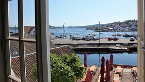 Une vue sur le port, visible depuis une fenêtre, avec des bateaux, un quai et une ville au loin.