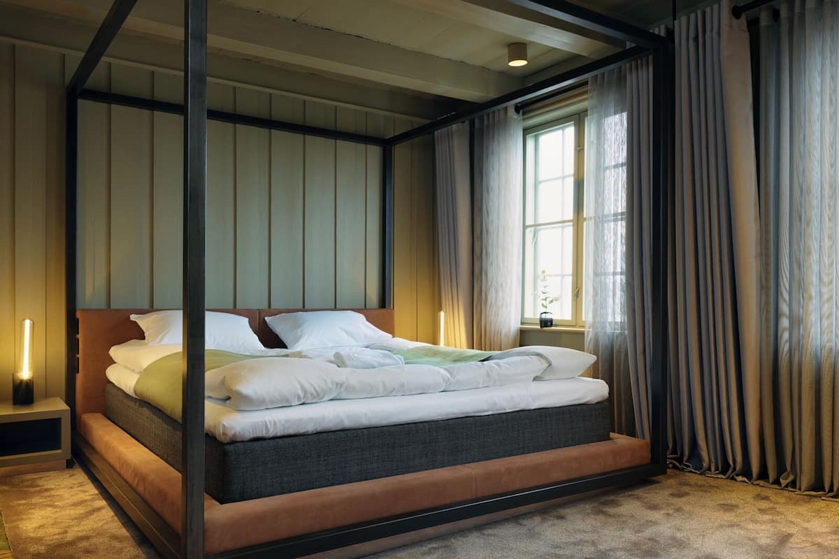 Ein modernes Schlafzimmer mit einem großen Bett, einem Nachttisch und einem Fenster mit Vorhängen.