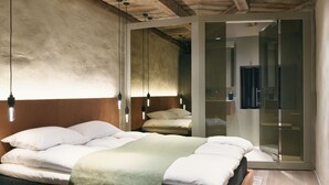 Une chambre moderne avec un plafond en bois, un lit recouvert de linge de lit blanc et une cloison en verre.