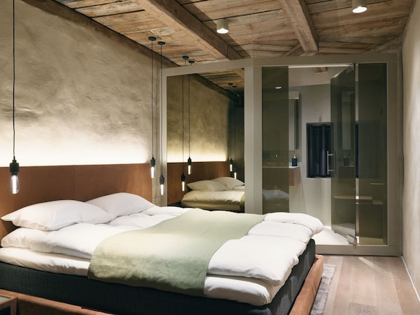 A modern bedroom with a wooden ceiling, a bed with white bedding, and a glass partition.