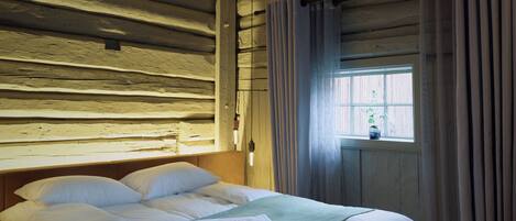 Una habitación tipo cabaña de madera con cama, cortinas y ventana con vistas.