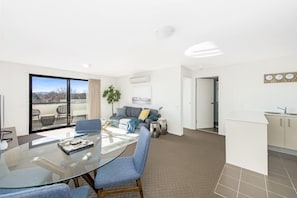 Relax in this stylish living area with a glass dining table, comfortable sofa, and a potted plant.