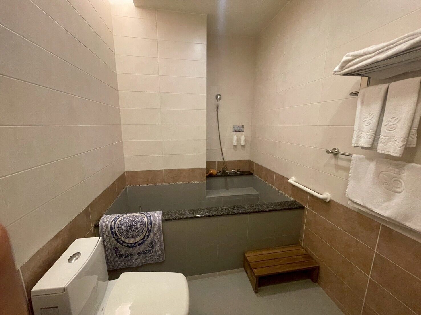 A small bathroom with a bathtub, toilet, and a towel rack.