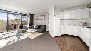 Un appartement moderne comprenant un salon, une cuisine et une grande porte-fenêtre coulissante donnant sur un balcon.