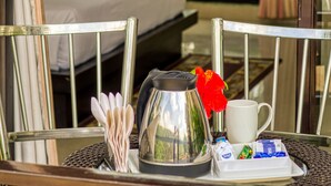 A hotel room with a bed, a coffee table with a kettle, cups, and a tray with breakfast items. - Corbett Solitaire (Ramnagar)