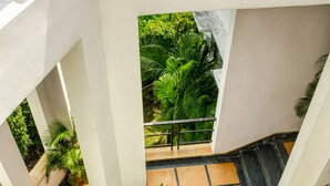 A multi-level indoor space with a central staircase surrounded by greenery and a tiled floor. - Corbett Solitaire (Ramnagar)