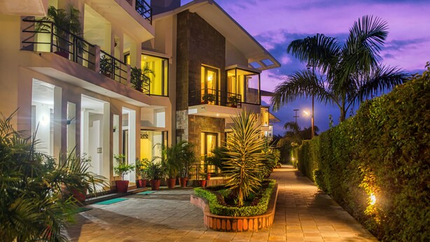 A modern multi-story building with balconies, a pool area, and well-maintained landscaping. - Corbett Solitaire (Ramnagar)