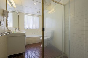 Un baño con ducha de vidrio, lavamanos e inodoro.