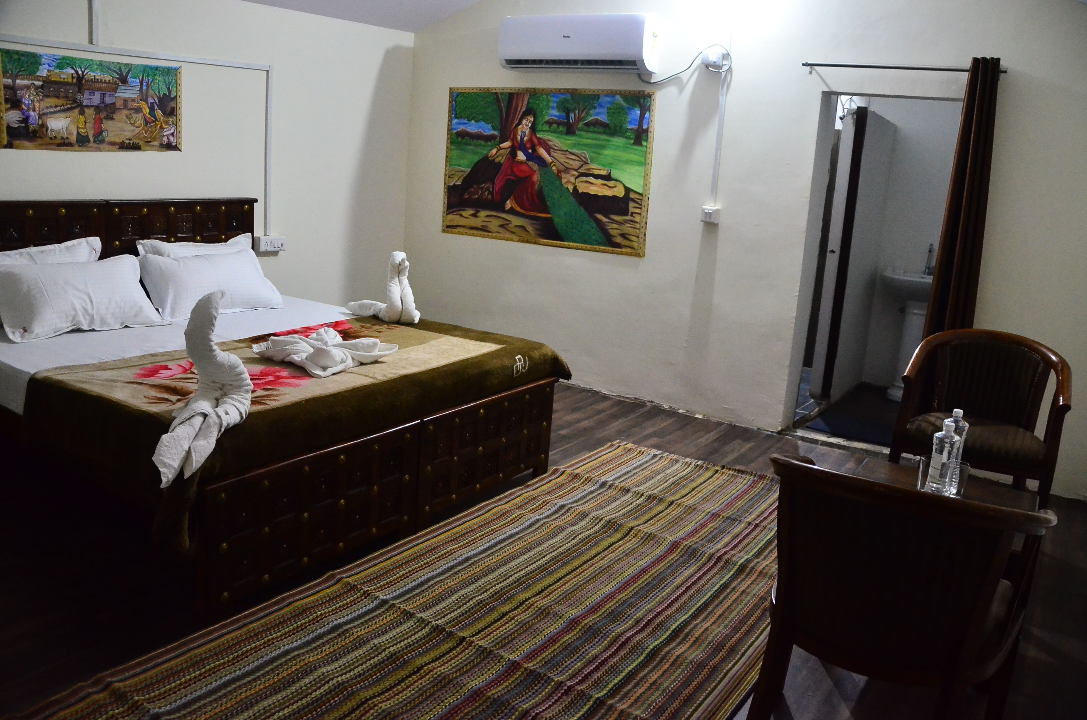 Une chambre d’hôtel avec un lit, une chaise, une table, un tableau et un appareil de climatisation.