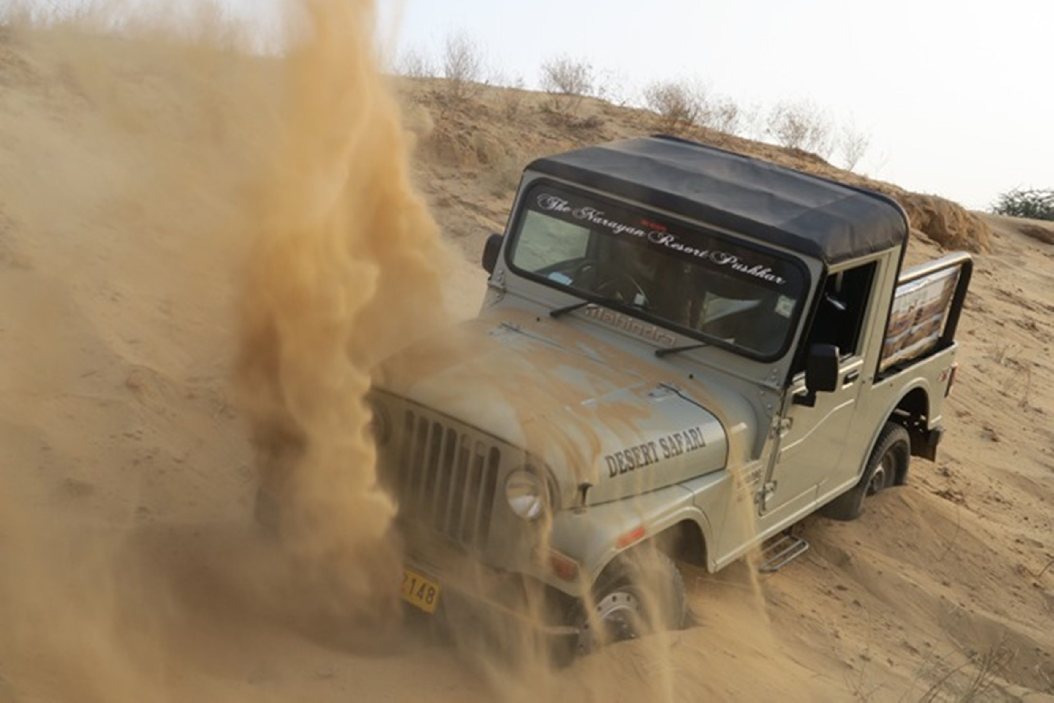 A desert safari vehicle driving through sand.