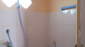 A small, basic bathroom with a toilet, a sink, and a shower. - Aranya Resort (Prakhon Chai)