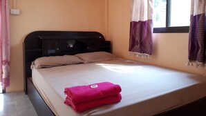 A single bed with a headboard, a window with curtains, and a wall socket. - Aranya Resort (Prakhon Chai)