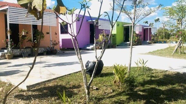 A residential area with colorful houses, a paved driveway, and some potted plants. - Aranya Resort (Prakhon Chai)