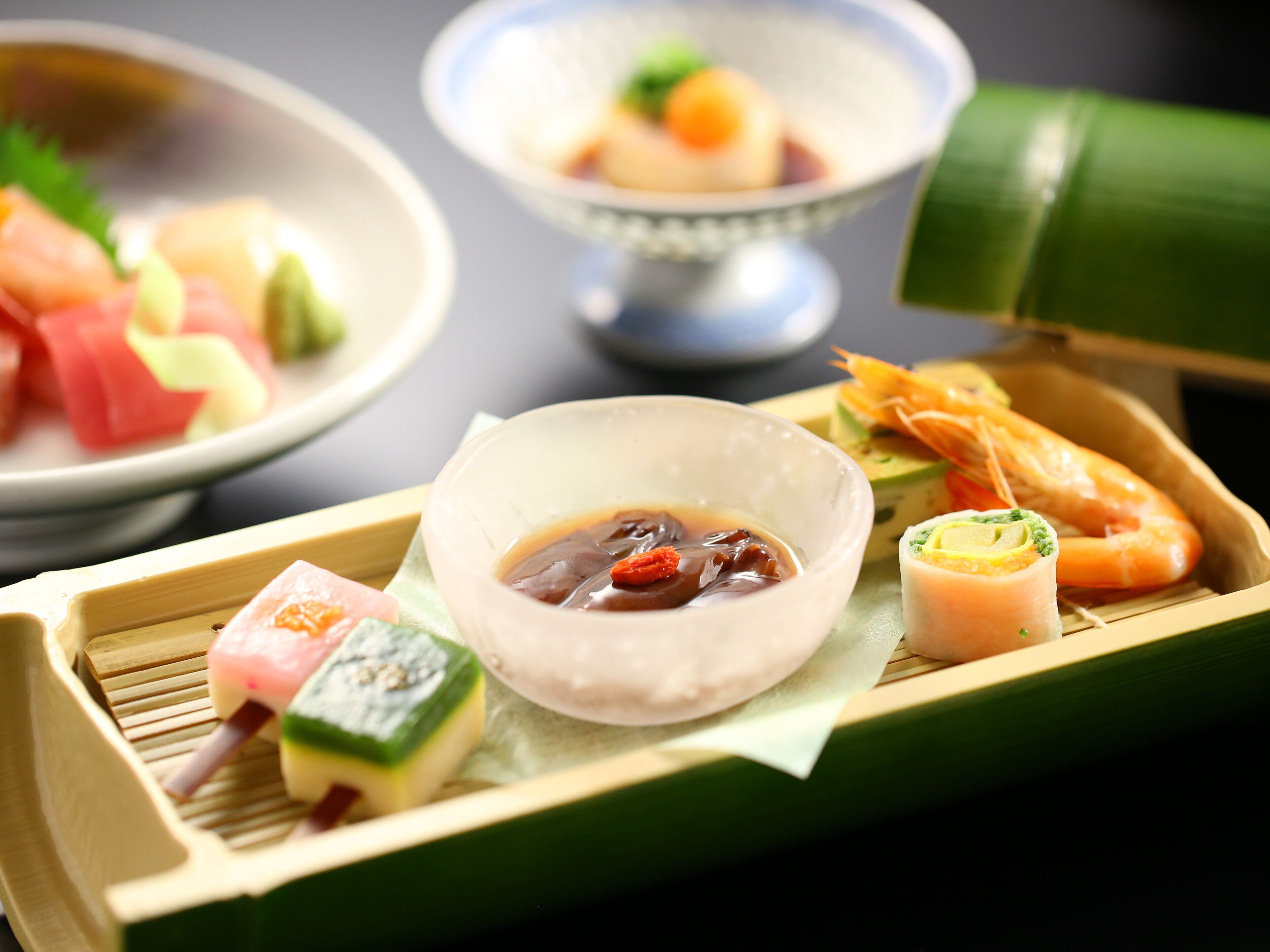 A traditional Japanese meal with various dishes including sashimi, vegetables, and a bowl of soup.