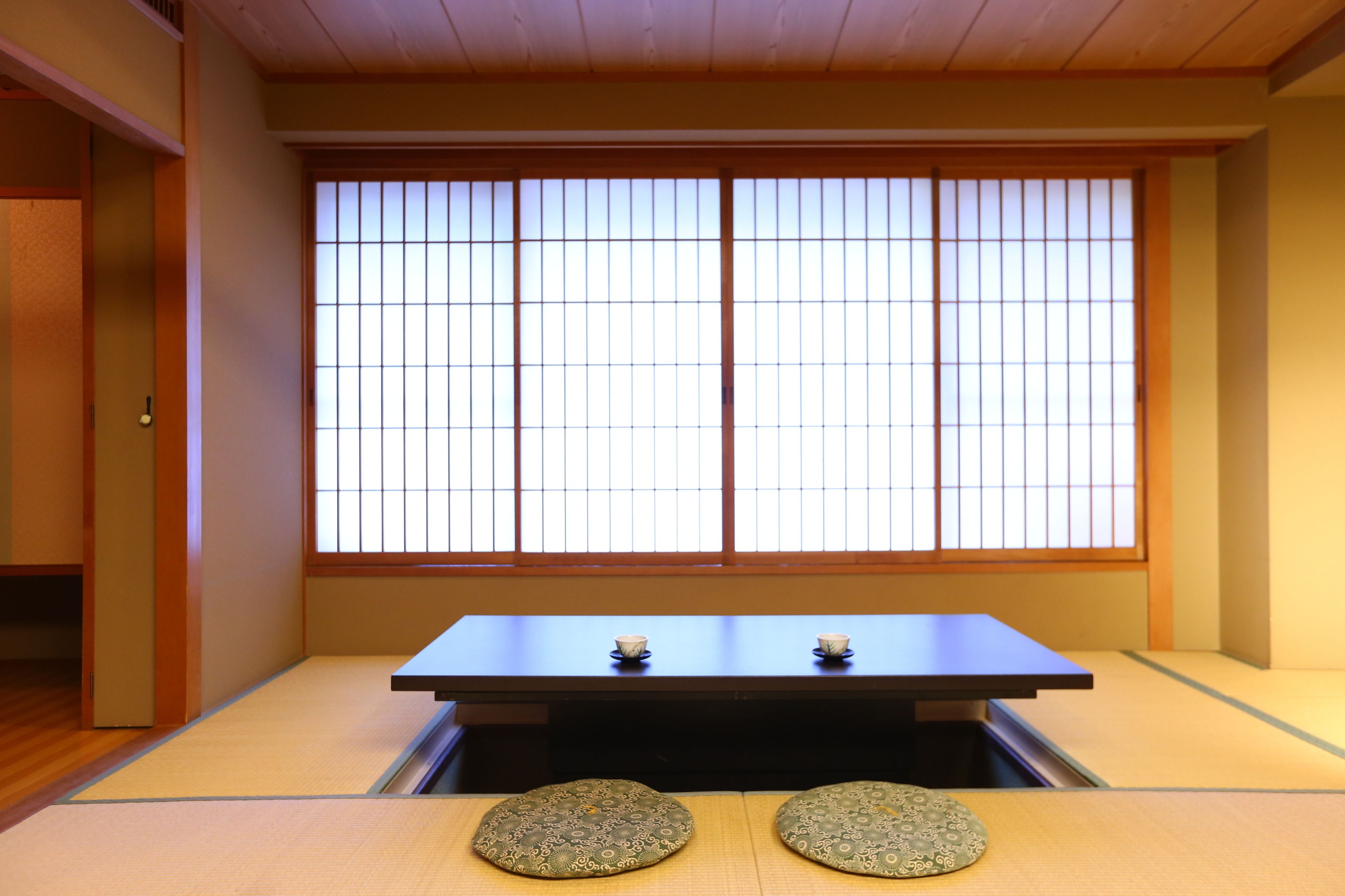 Une pièce de style japonais traditionnel, avec un sol recouvert de tatamis, une table basse et des paravents en papier de riz (shoji).