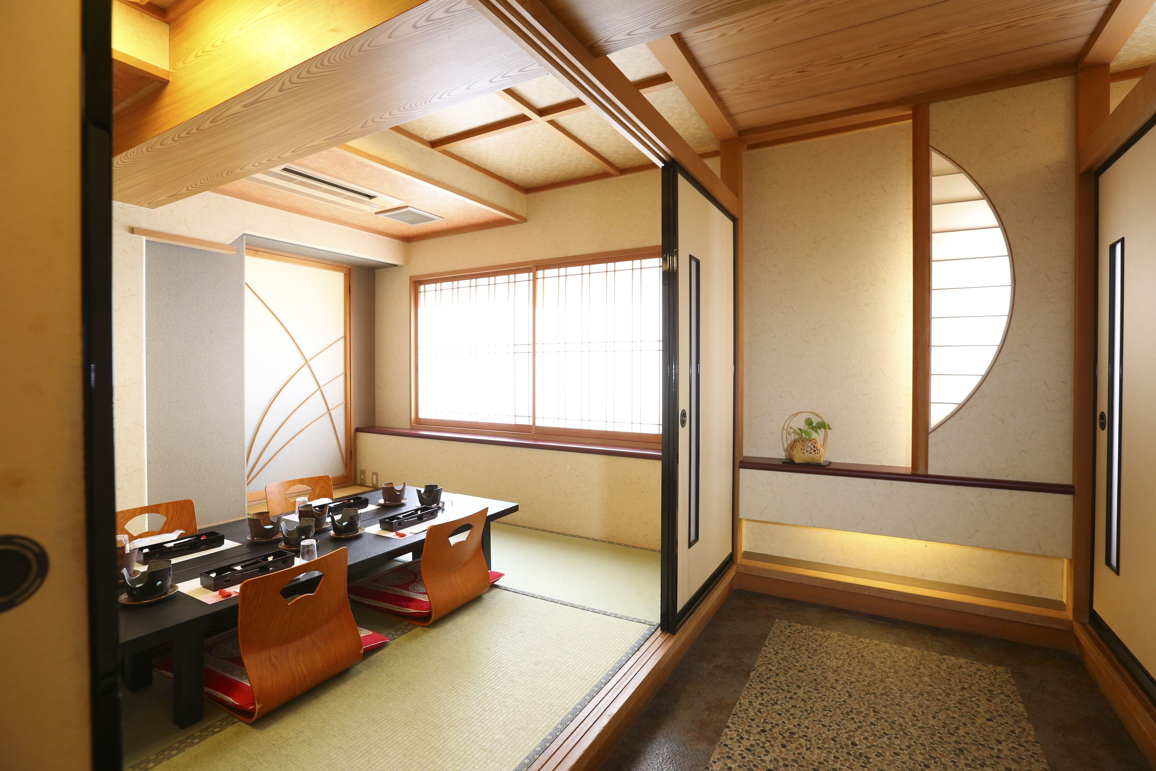 Een traditionele Japanse kamer met tatami vloeren, een lage tafel met kussens en schuifdeuren.