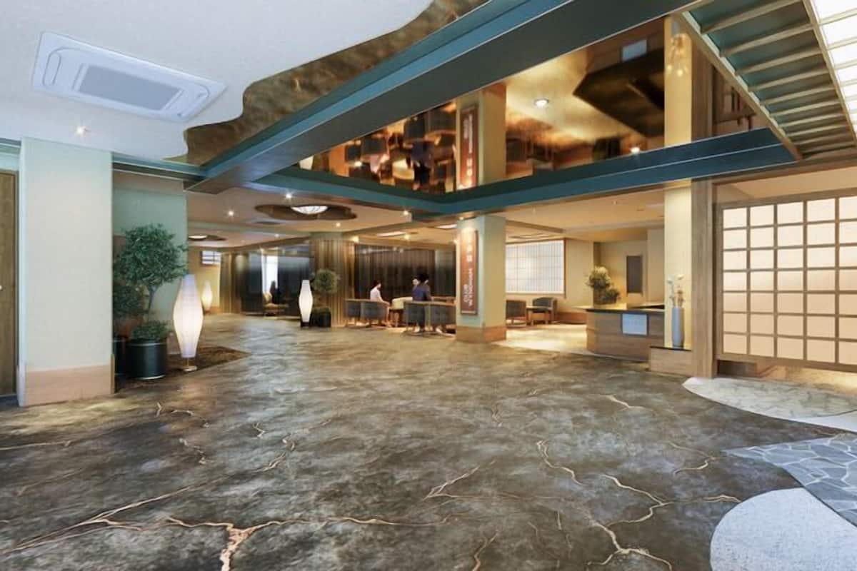 A spacious lobby with a high ceiling, a reception desk, and a staircase leading to upper floors.