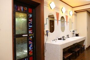 Un baño con un espejo grande, dos lavamanos y bancos.