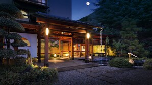 A traditional Japanese house with a wooden structure, a garden with gravel paths, and a moon in the sky. - Club Wyndham Chikumakan Nagano (Chikuma)