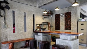 A bar area with a wooden counter, stools, and a clock on the wall. - Sirah Hometel - Hostel (Ko Pha-ngan)