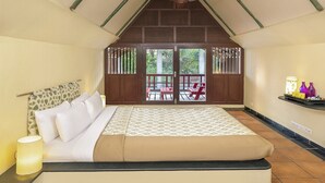 A bedroom with a bed, a ceiling fan, a window with a view of the outside, and a shelf with items on the wall. - Mango Hill Pondicherry (Vanur)