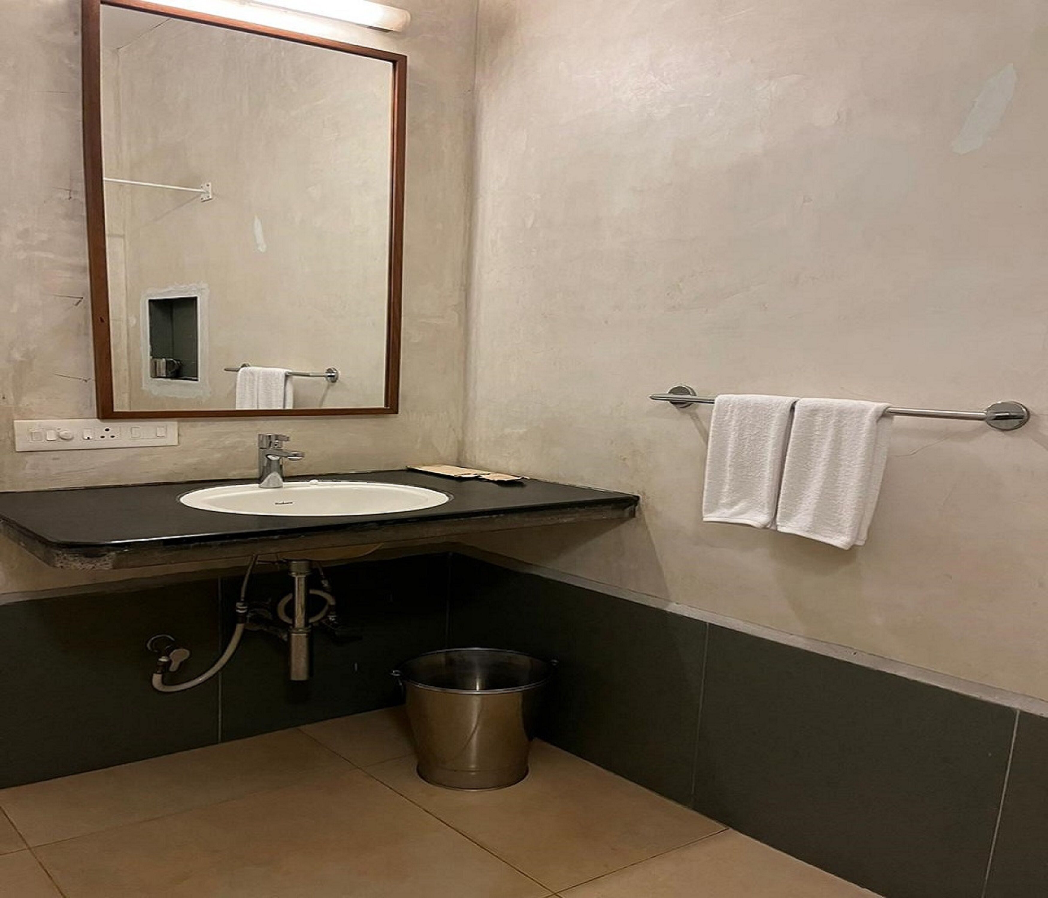 A bathroom with a sink, mirror, towel rack, and a trash can.