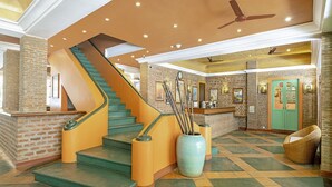 A hotel lobby with a staircase, a reception desk, and a green door. - Mango Hill Pondicherry (Vanur)