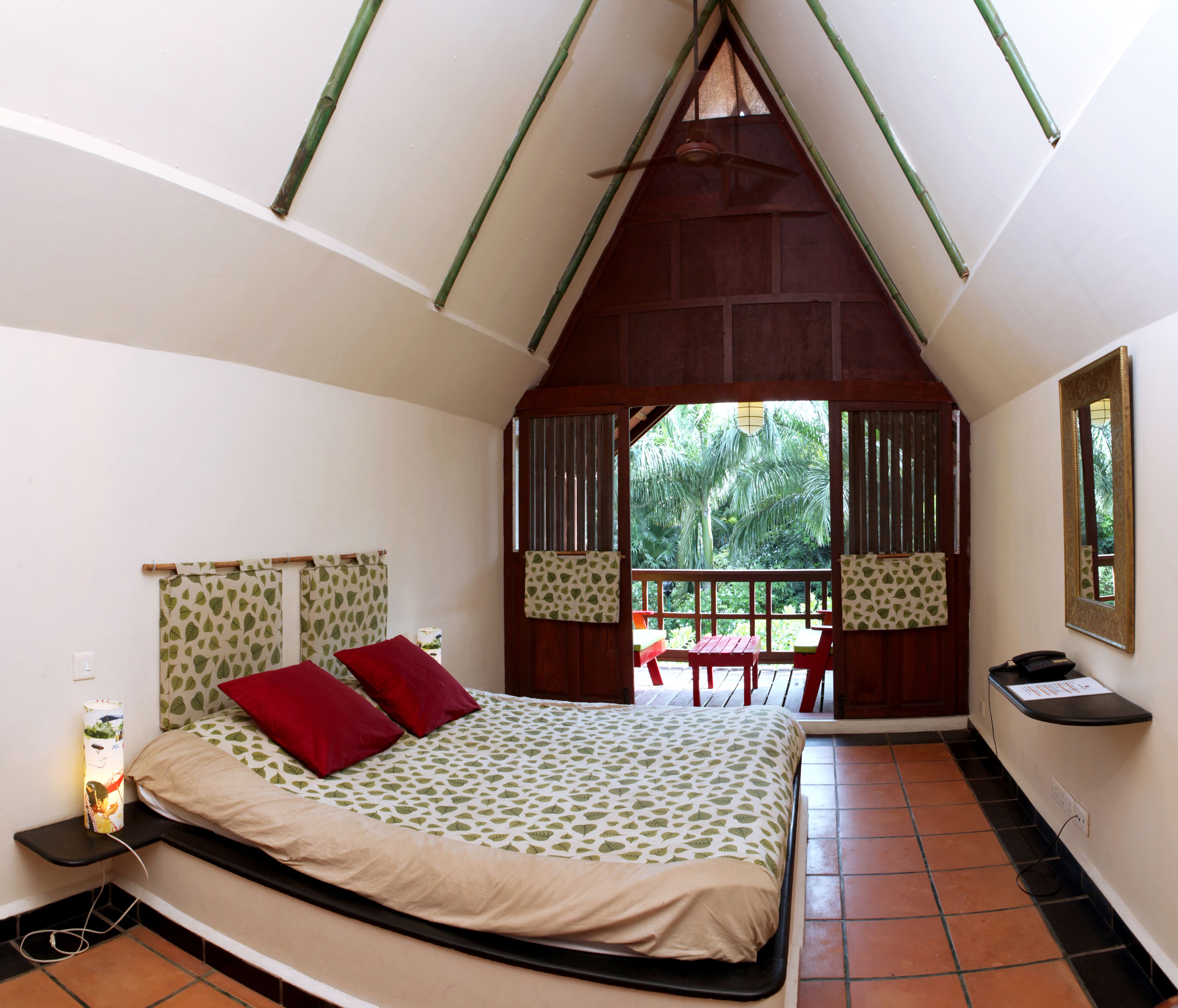 A bedroom with a bed, a desk, and a view of the outdoors.