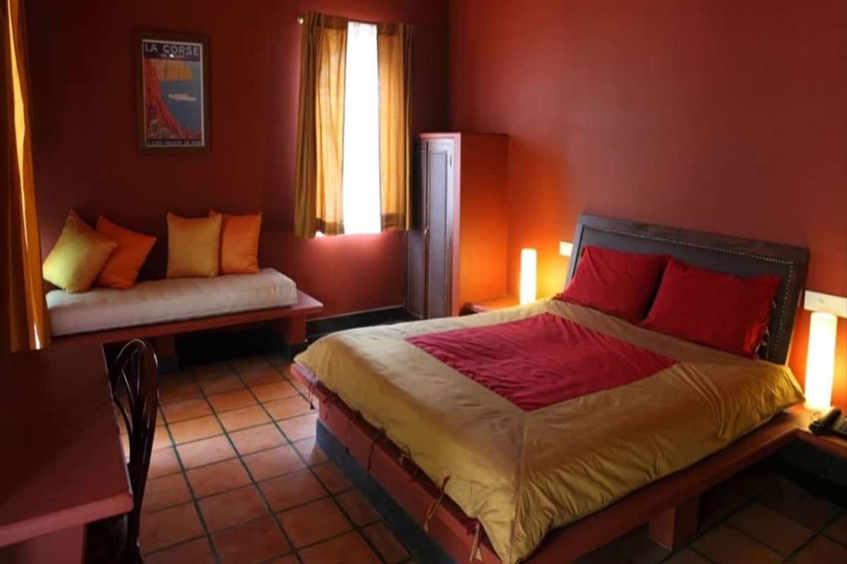 A hotel room with a bed, a sofa, a desk, and a cabinet.