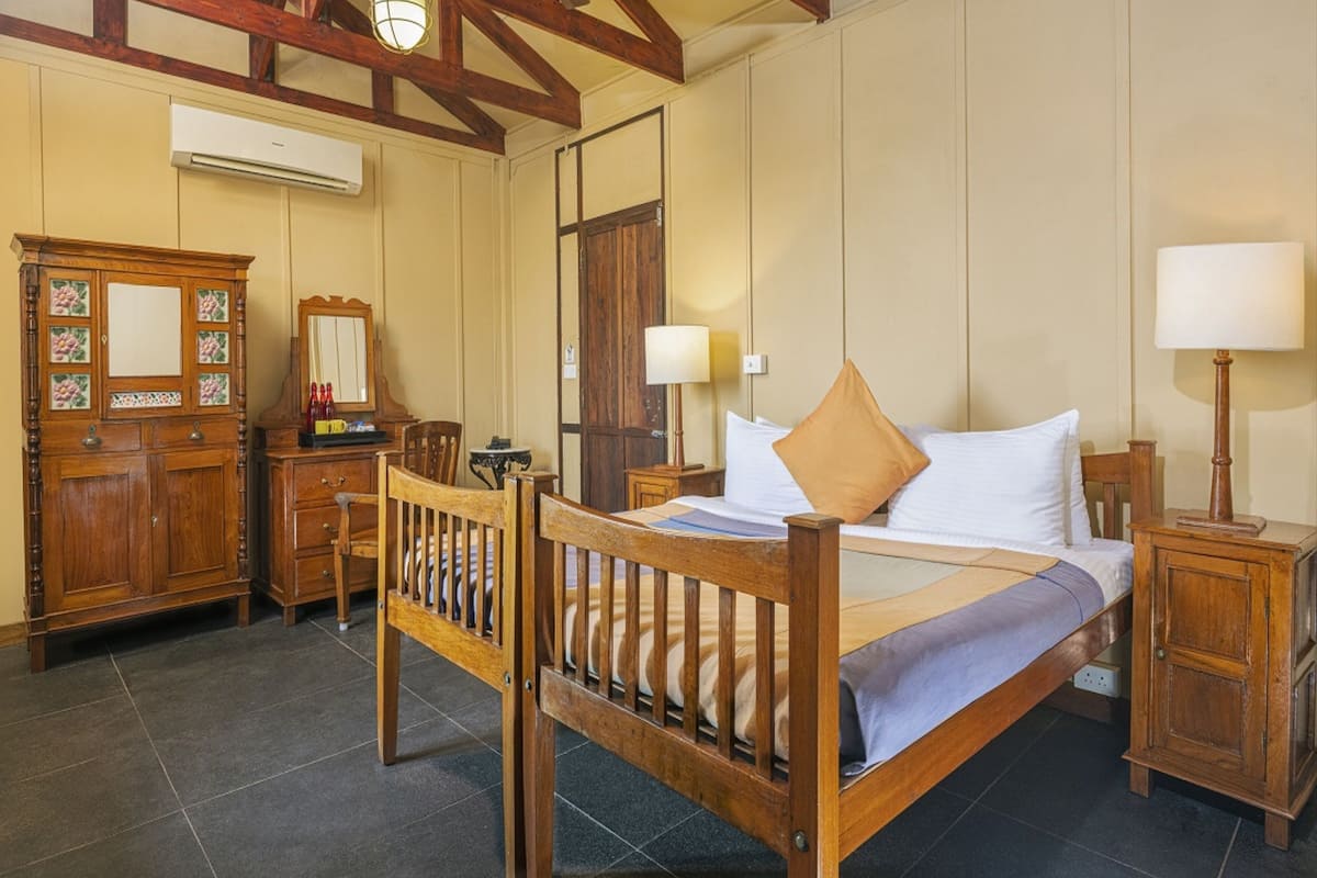 A bedroom with a wooden bed, a nightstand, a dresser, and a mirror.