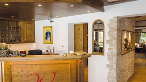 Uma área de bar com balcão de madeira, um quadro com a imagem de um cão e uma parede de pedra.