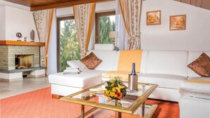Uma sala de estar com lareira, sofá branco e mesa de centro de vidro com flores.