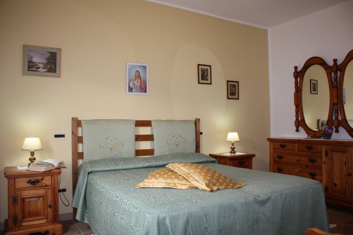 Quarto com cama, duas mesas de cabeceira, penteadeira e espelho.