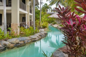 A resort with a swimming pool, stone walls, and tropical plants.