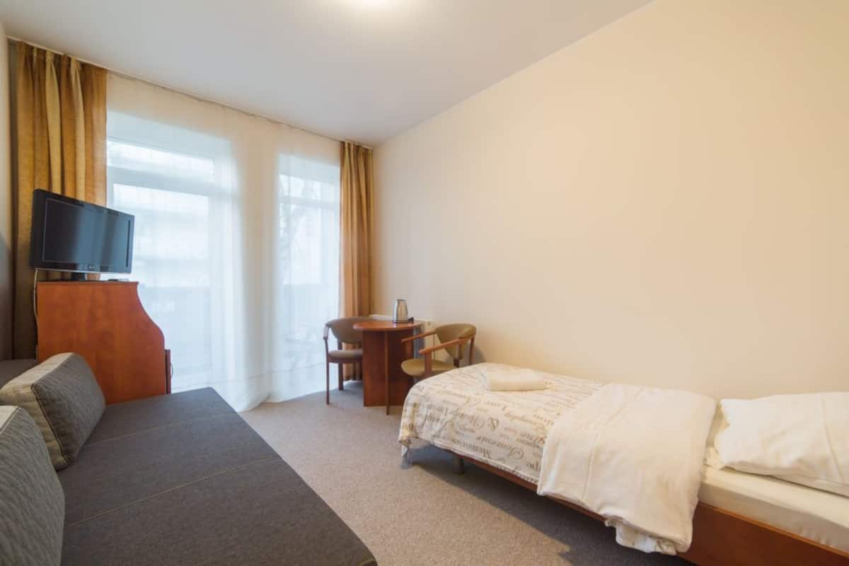 Ein Hotelzimmer mit Bett, Sofa, Schreibtisch und Fernseher.